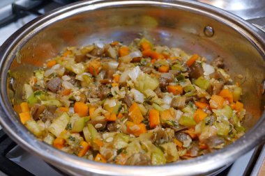 Gaz sobasında sebze güveci pişirilir. Ragout metal tavada pişiyor. Sebze yahnisi: patlıcan, kabak, salatalık, havuç, sarı biber, beyaz ve yeşil soğan, dereotu, maydanoz, tuz, baharat