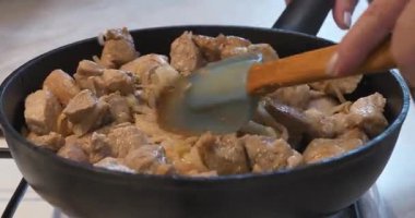 Aşçı et parçalarını fırında tavada soğanla karıştırır.