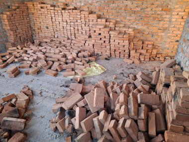 Tuğlalar yere saçılmış. Tuğla duvarları olan bitmemiş bir kulübenin içinde. Oturulmayan, tamamlanmamış bir bina