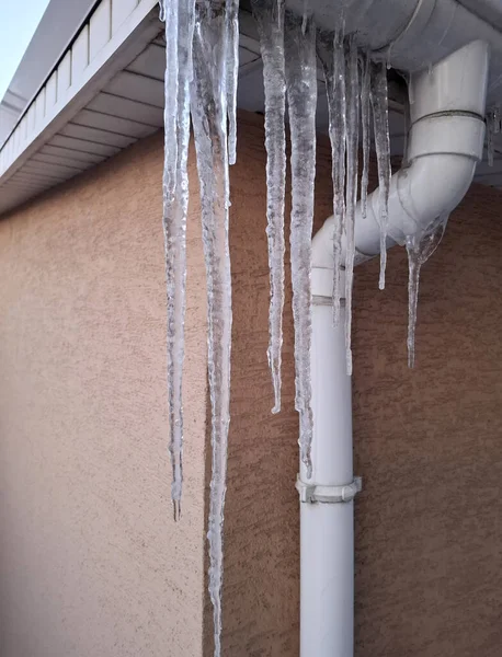 Evin çatısında büyük uzun buz sarkıtları asılı. Soğuk kış, buz oluşumu