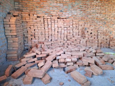 Tuğlalar yere saçılmış. Tuğladan duvarları olan bitmemiş bir kulübenin içi. Oturulmayan, tamamlanmamış bir bina