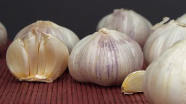 Sarımsak koyu arka planda döner. Sarımsak, Allium sativum, Allium cinsindeki soğan çiçekli bitkiler. Sarımsak - sağlık için yararlı özelliklere sahip çok sağlıklı bir ürün