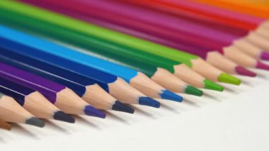 Beyaz masanın üzerinde farklı renklerde güzel yeni kalemler yatıyor. Gökkuşağı renginde çok renkli kalemler