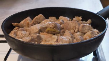 Kızarmış et. Soğanlı et parçaları gaz sobasında siyah tavada kızarıyor.