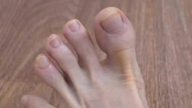 Yetişkin bir adamın güzel ayakları ve ayak parmakları. Kesilmemiş tırnakları olan ideal erkek ayağı. Adam ayak parmaklarını oynatıyor, yakın çekim video.