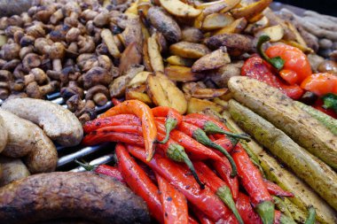 Çeşitli kızarmış sıcak yiyecekler. Kırmızı biber, kabak, patates, sosis ve mantar. Dışarıdaki fast food restoranında yemek.
