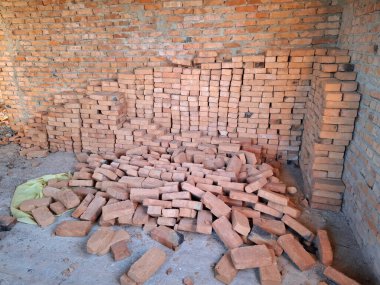 Tuğlalar yere saçılmış. Tuğla duvarları olan bitmemiş bir kulübenin içinde. Oturulmayan, tamamlanmamış bir bina