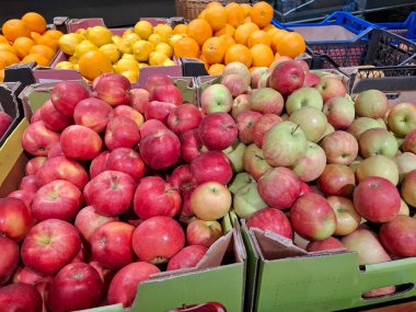 Marketteki kutularda kırmızı ve yeşil elmalar, portakallar ve limonlar. Süpermarket raflarında meyveler. Market tezgahları olgun taze meyvelerle dolu.