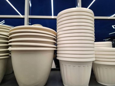 Beyaz plastik saksılar bir çiçekçide satılır. Süpermarket raflarında büyük saksılar