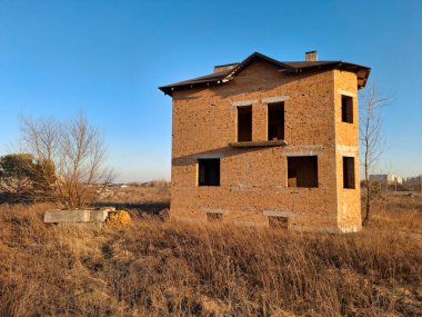 Kırmızı tuğlalı duvarları ve pencereleri olan bitmemiş bir evin dış cephesi. Yerleşim olmayan, tamamlanmamış bir bina.
