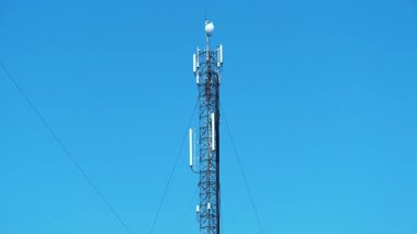 İşçiler baz istasyonuna hizmet veriyor. İşçiler baz istasyonunu onarıyor. Cep telefonu kulesindeki işçiler. İşteki bakım personeli. Mavi arkaplandaki baz istasyonu