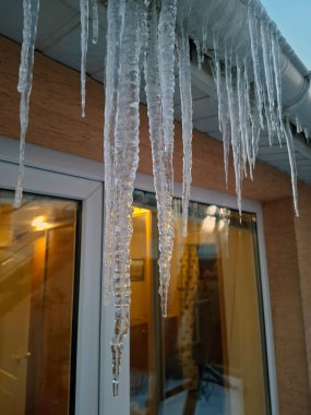 Kır evinin pencerelerinden sarkan büyük buz sarkıtları