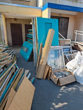 Çok katlı bir binanın eski Sovyet kapı ve pencerelerinin değiştirilmesi. Eski ahşap kapılar apartmanın girişinin yanında duruyor. Yeni plastik pencere ve kapılarla değiştir