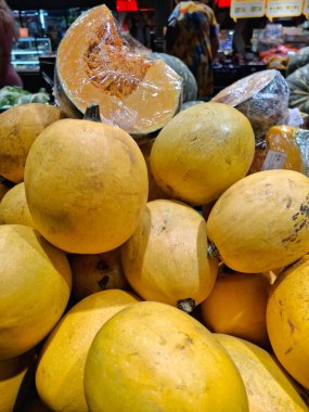 Süpermarkette sarı balkabakları. Marketlerde meyve ve sebzeler var. Market tezgahları olgun meyve ve mevsimlik sebzelerle dolu.