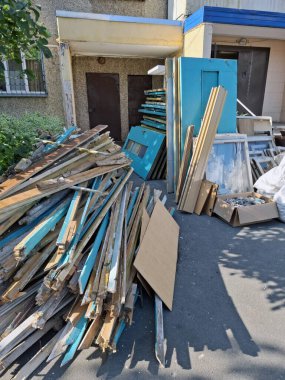 Konut evindeki eski kapı ve pencerelerin değiştirilmesi. Eski ahşap kapılar apartmanın girişinin yanında duruyor. Yeni plastik pencere ve kapılarla değiştir