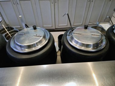 Fast food restoranındaki sıcak taze yemek için kepçe ve metal kapaklı çorba kapları.