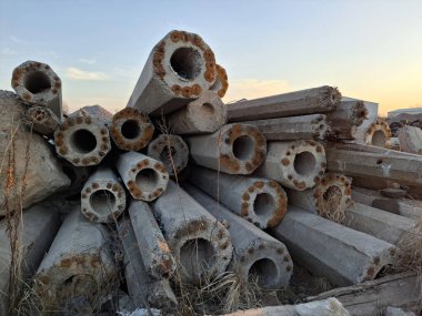 Çöplükte güçlendirilmiş eski beton direkler.