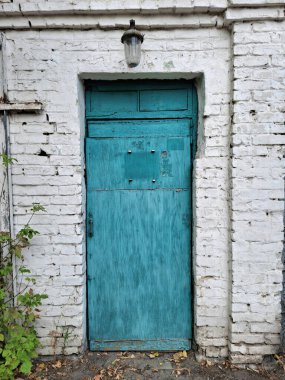 Eski yeşil ahşap kapı. Kapının üstünde fener asılı.