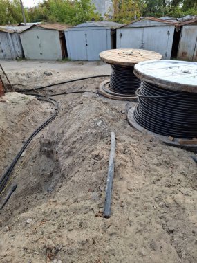 Elektrik kabloları siperlere konur. Yeraltında yatmak için kablolar açılır. Büyük makaralı siyah kablolar