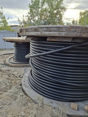 Büyük elektrik kablosu makaraları. Güç kablosu döşeniyor. Büyük makaralı siyah kablolar. Kurulum için siyah elektrik kabloları sökülüyor