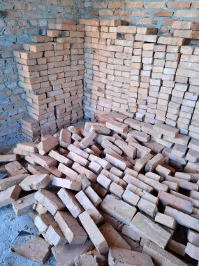 Tuğlalar yere saçılmış. Tuğladan duvarları olan bitmemiş bir kulübenin içi. Yerleşim olmayan, tamamlanmamış bir bina.