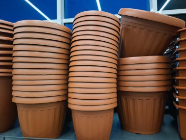 Plastik saksılar bir çiçekçide satılır. Raflardaki büyük saksılar