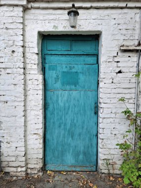 Eski mavi kapalı kapı. Sonbahar yaprakları girişe saçıldı.