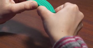 Yumuşak modelleme kiline sahip bir çocuğun elleri. Bir çocuk elinde turkuaz plastiksi tutuyor. Çocuk parmaklarıyla kil yontuyor. Minicik ellerde yumuşak plasticin. Yumuşak balçığa bastıran minik parmaklar