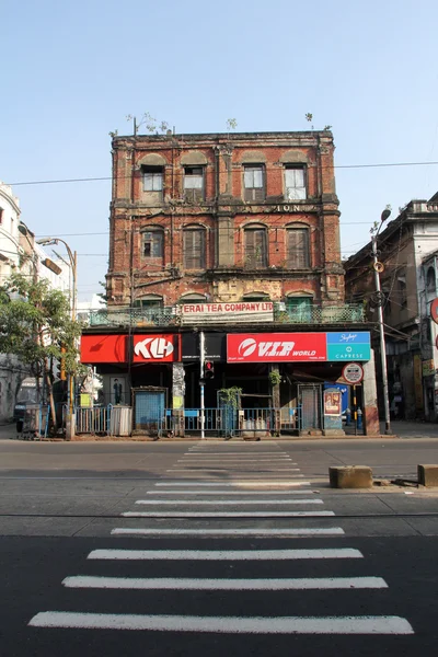 Un envejecido, decadente, ex bloque de viviendas coloniales con tiendas en Calcuta, Bengala Occidental, India — Foto de Stock