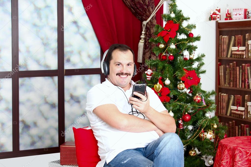 Mature man listening to music on headphones  near a New Year tre