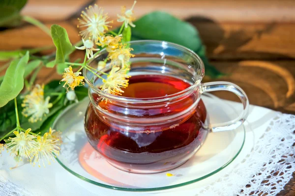 Xícara com chá de tília e flores na mesa de madeira — Fotografia de Stock