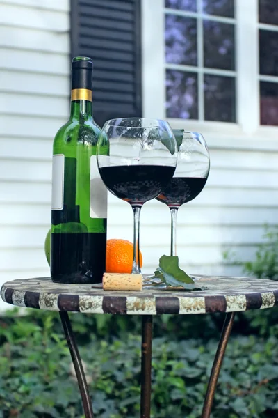 Garrafa de vinho e copos em uma mesa de jardim — Fotografia de Stock