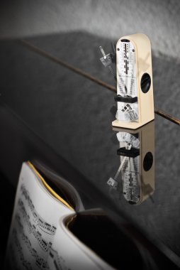 Piyano üzerinde metronom duran.