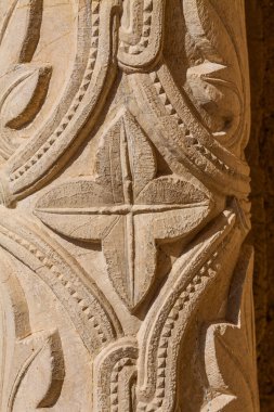 A colorful tiled street sign reading  is mounted on a yellow wall, with a smaller metal sign below it