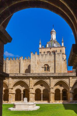 Kemerli taştan bir fıskiyesi olan güneşli bir avlu, parlak mavi gökyüzüne karşı sertleştirilmiş kubbeli tarihi bir binayı gözler önüne seriyor.