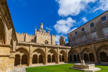 Merkezi taştan bir fıskiyesi olan güneşli bir avlu, üzerinde parlak mavi gökyüzü bulunan tarihi bir kubbe bulunan kemerli manastırlarla çevrilidir..