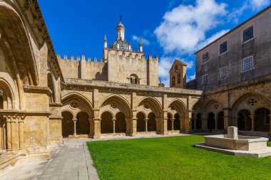 Merkezi taştan bir fıskiyesi olan güneşli bir avlu, üzerinde parlak mavi gökyüzü bulunan tarihi bir kubbe bulunan kemerli manastırlarla çevrilidir..