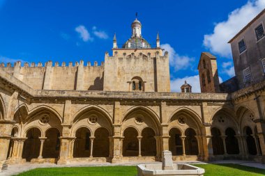 Merkezi taştan bir fıskiyesi olan güneşli bir avlu, üzerinde parlak mavi gökyüzü bulunan tarihi bir kubbe bulunan kemerli manastırlarla çevrilidir..