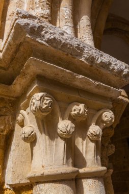 Süslü, yıpranmış taştan bir başkentin yakın çekimi. Karmaşık çiçek ve kaydırma oymaları tarihi bir binada bir sütunu destekliyor.