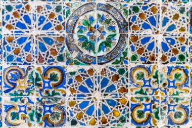 Geleneksel seramik fayans mozaiğinin canlı, yakın plan görüntüsü. Mavi, yeşil ve toprak tonlarda zengin bir geometrik ve çiçek desenleri dizisi.