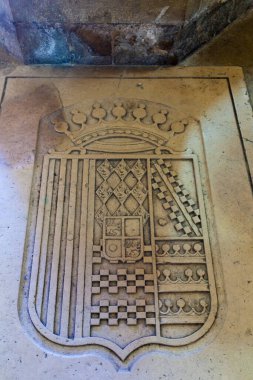 Ayrıntılı kraliyet kalkanının eski mimari bir yüzeye yerleştirilmiş, bir taç ile kaplanmış yıpranmış bir taş oyması..