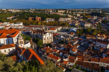 Leiria. Geniş bir hava manzarası, ikonik kırmızı kiremitli çatıları, beyaz yıkanmış binaları ve çarpıcı ve bulutlu gökyüzünün altında yemyeşil tepeler arasında yuva yapmış seçkin bir kilisesi olan tarihi bir Avrupa kasabasını yakalıyor..