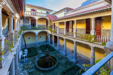 Biscainhos Müzesi. - Braga. Bu yüksek açılı çekim, iki katlı zarif taş sütunlar ve kemerli geçitlerle tarihi bir binanın iç avlusunu yakalıyor. Merkezi avluda bir taş çeşme ve manikürlü bahçe var.