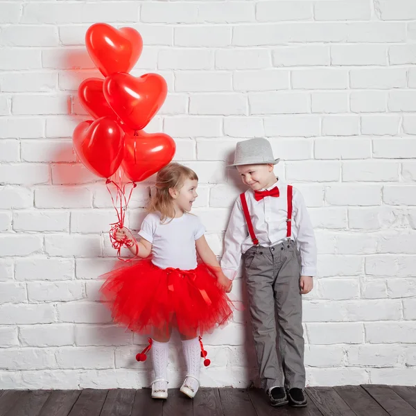 Miúdos a segurar e a apanhar balões cardíacos. Dia dos Namorados e conceito de amor, no fundo branco — Fotografia de Stock