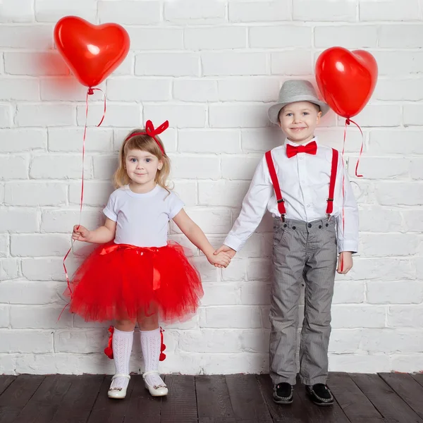 Miúdos a segurar e a apanhar balões cardíacos. Dia dos Namorados e conceito de amor, no fundo branco — Fotografia de Stock