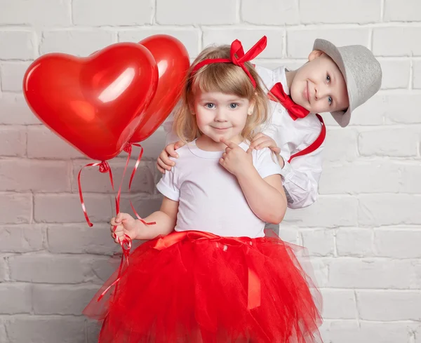 Little kids holding and picking up heart balloons. Valentine's Day and love concept, on white background — Stock Photo, Image