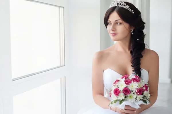 Mooie brunette bruid in een trouwjurk en een kroon op haar hoofd. Schoonheid gezicht. — Stockfoto