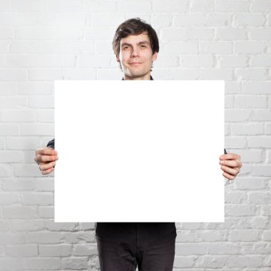 genç adam tuğla odasında posteri holding