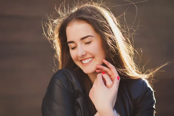 Härliga porträtt av ganska leende kvinna. Flickans hår bakgrundsbelyst av gula heta solljuset. Hon slöt ögonen och ler. — Stockfoto