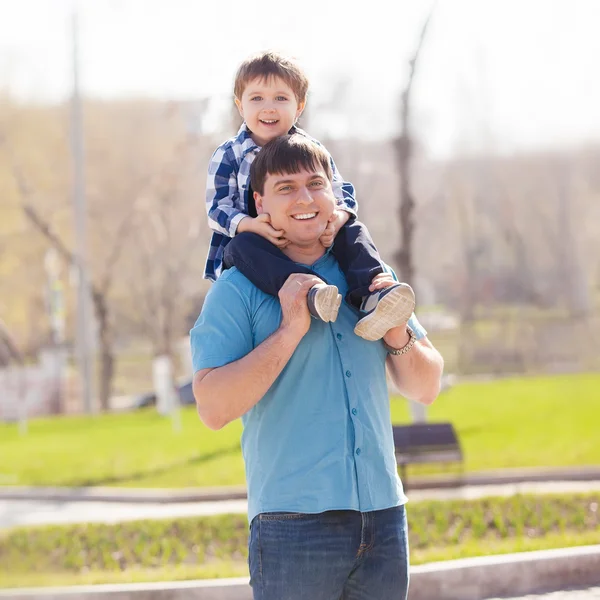 Hijo sobre los hombros de los padres en el parque divirtiéndose juntos — Foto de Stock